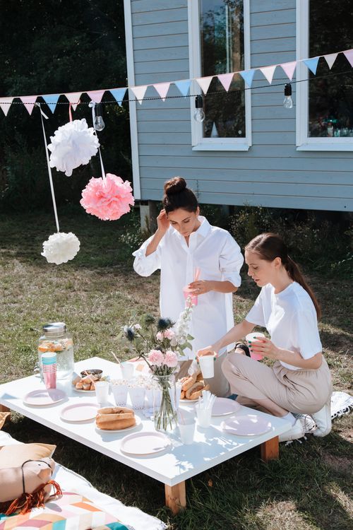 Free Two women enjoying a summer garden party with elegant decorations and refreshments. Stock Photo