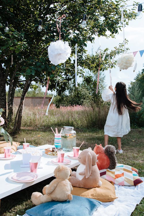 A Girl in White Dress Playing with Party Decorations