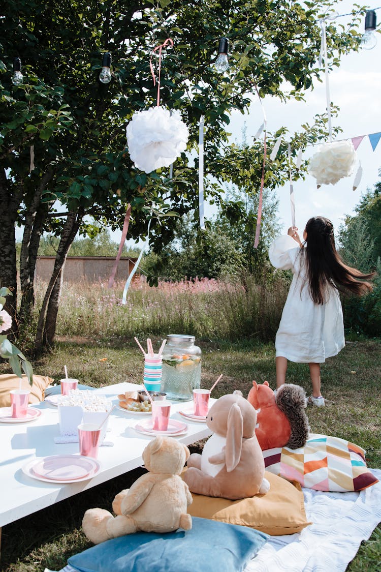 A Girl In White Dress Playing With Party Decorations