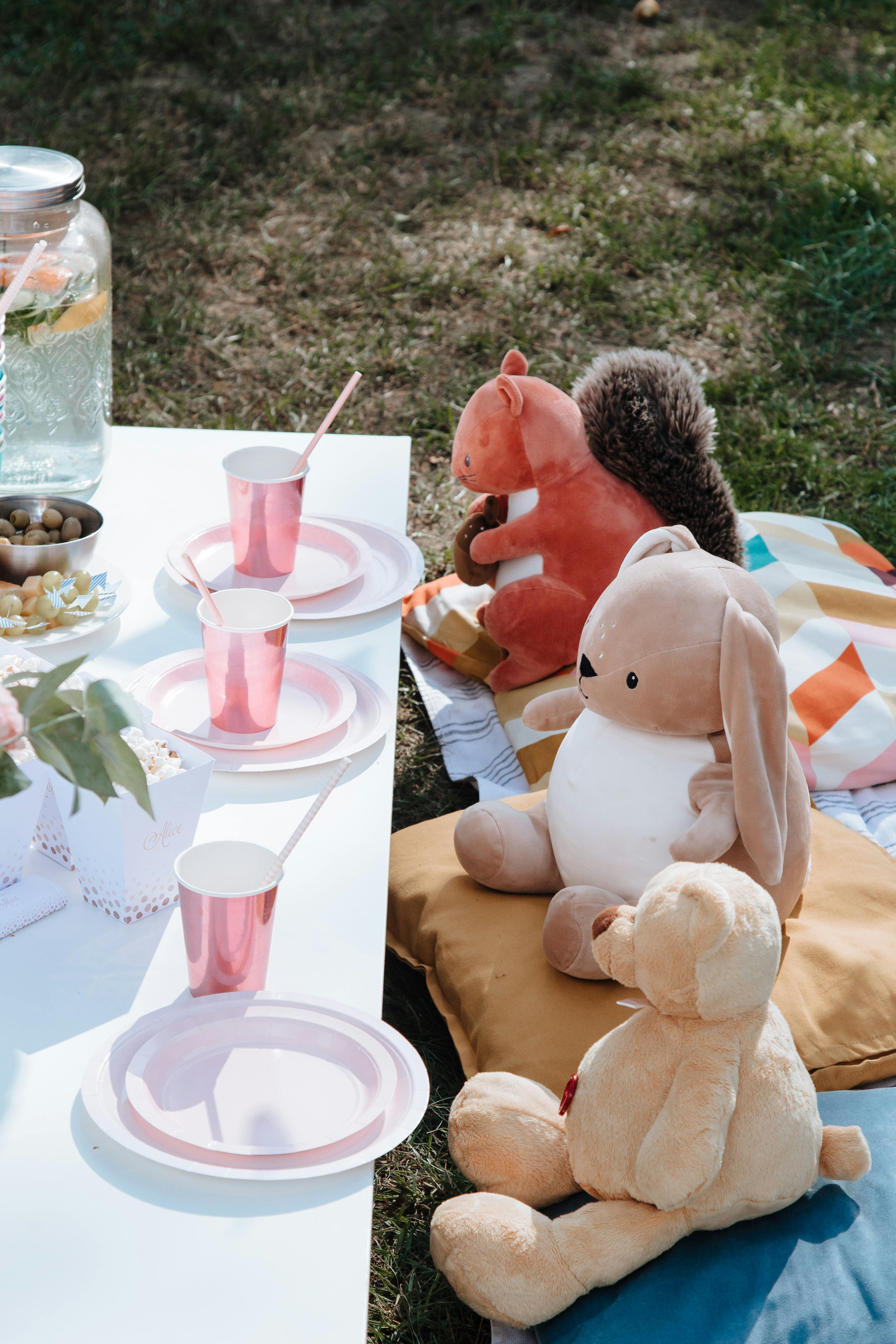 stuffed toys sitting on throw pillows in front of a picnic table