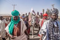 Vibrant celebration with men in traditional attire and turbans during a parade in Zaria, Nigeria.