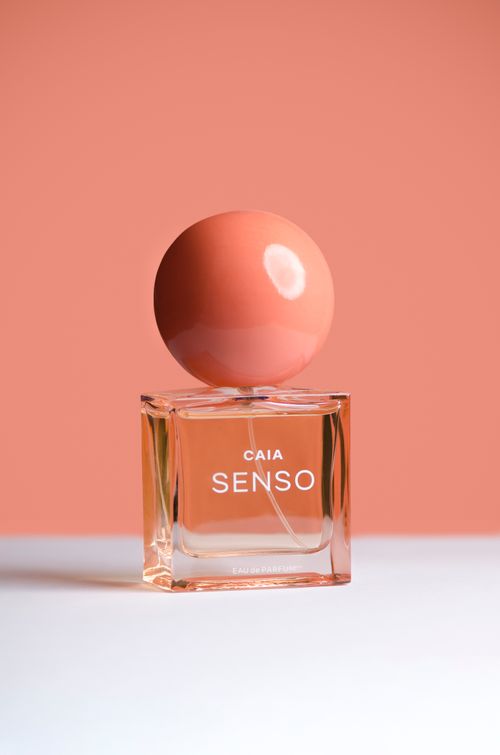 Free Elegant perfume bottle with coral sphere cap on a white surface against a pink background. Stock Photo