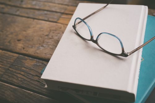 Free Close-up of vintage glasses on a stack of hardcover books on a wooden table. Stock Photo
