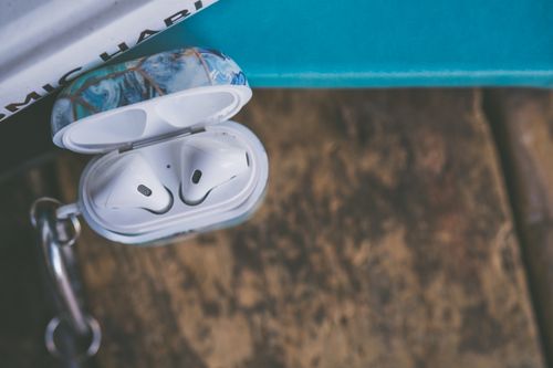 Free Close-up of wireless earbuds in an open case with decorative design, placed on a wooden surface. Stock Photo