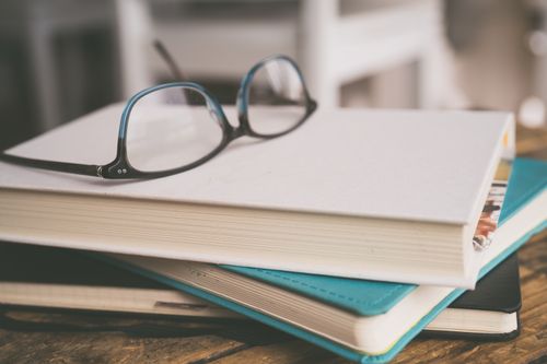 Free Eyeglasses on a stack of books in a cozy study setting, focusing on learning. Stock Photo