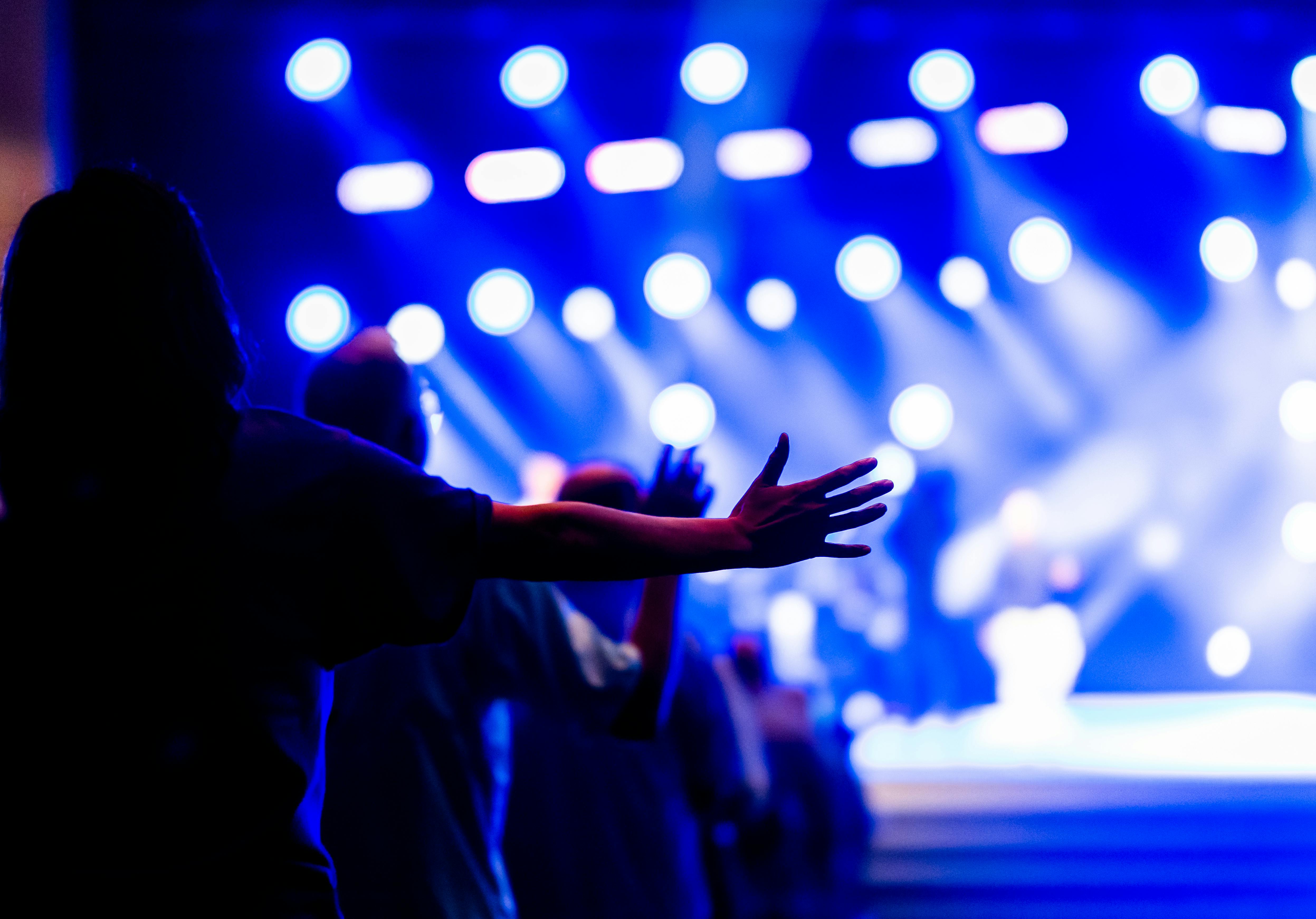 Young Ghanaians raising hands in worship at Christ Embassy Loveworld Arena Ho with modern stage lighting