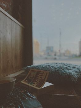 A cozy reading nook by the window with a book and fluffy pillow.