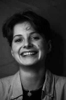 Black and white portrait of a smiling woman with short hair, conveying happiness.
