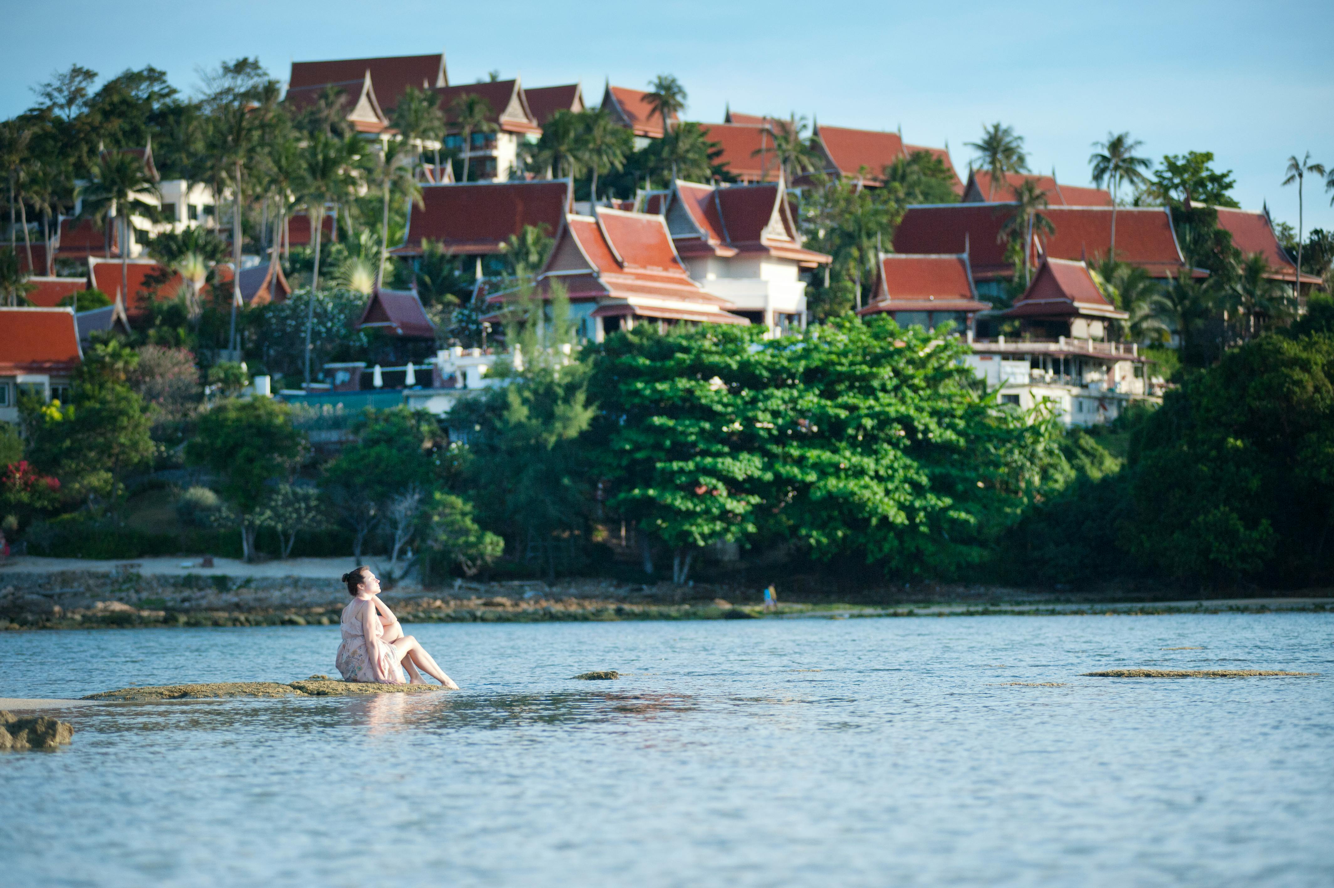 woman on rock beside body of water