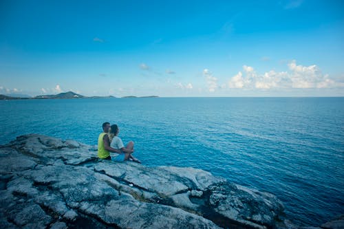 Man and Woman Sitting Near Body of Water