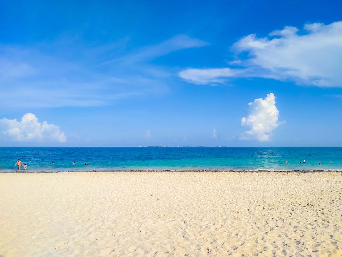 Un hermoso día soleado en la playa de Cancún con océano turquesa y cielos azules despejados.