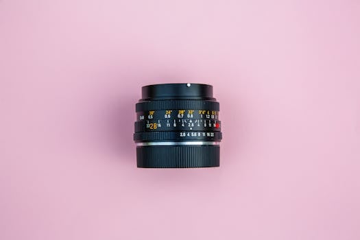 软粉色背景上，复古相机镜头的顶视图被单独呈现，以强调经典摄影设备