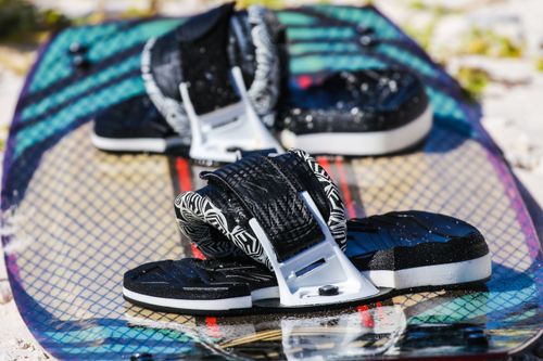 Free A close-up of a colorful surfboard with black bindings on a beach. Stock Photo