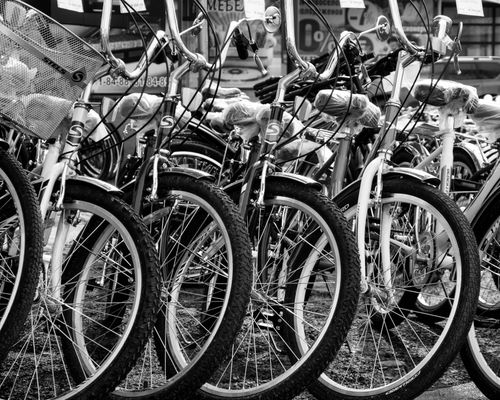 Free Black and white image of parked vintage bicycles on a street, highlighting spokes and handlebars. Stock Photo