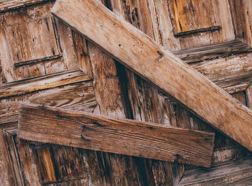 Selective Photo of Two Brown Wood Lumbers barring a door