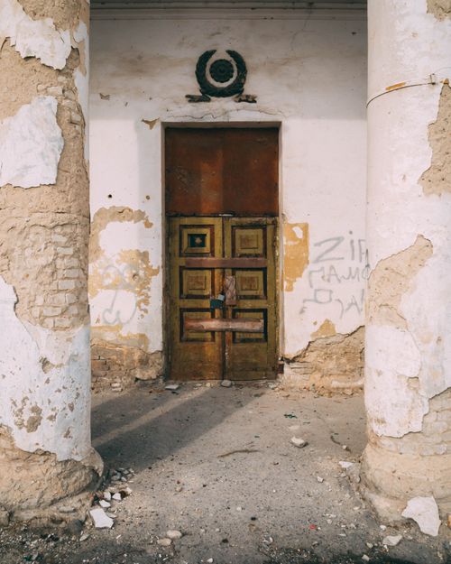 Free A weathered doorway with cracked pillars, featuring graffiti and signs of decay. Stock Photo