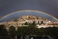 一道充满活力的彩虹横跨风景如画的山坡小镇，捕捉了自然美景的瞬间