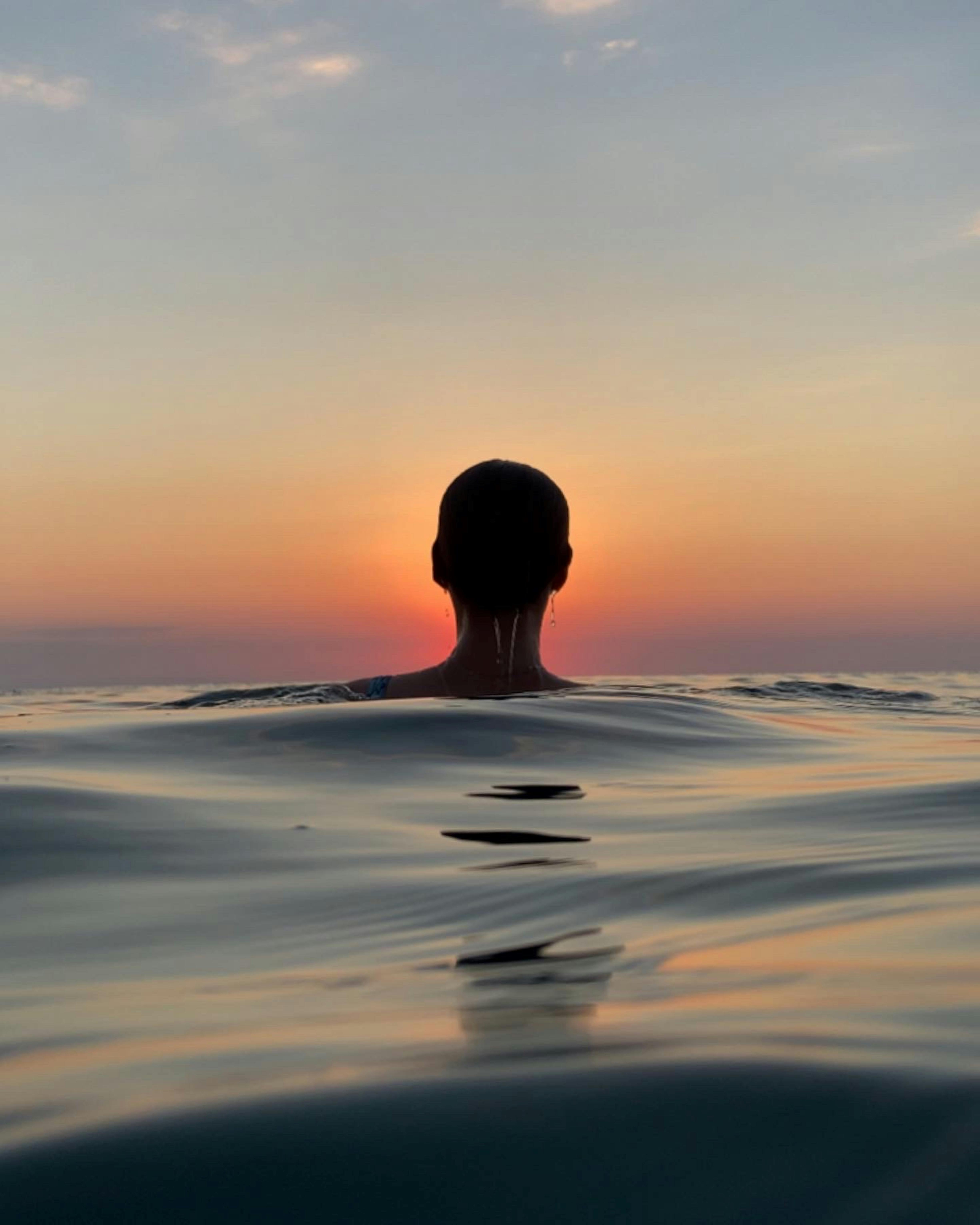 silhouette of a woman bathing in a lake at sunset