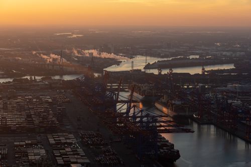 Free Stunning aerial view of Hamburg's bustling port during sunrise, showcasing cranes and container ships. Stock Photo