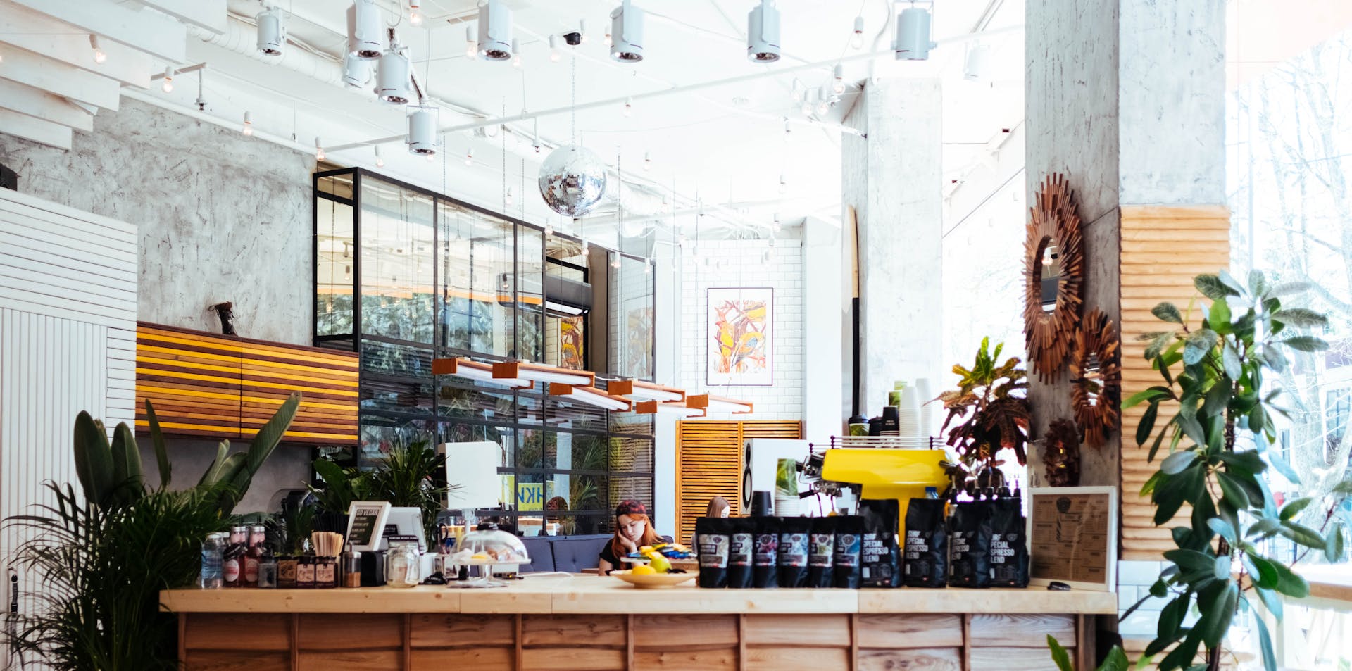 Stylish coffee shop interior with bright lighting and lush plants in Sochi, Russia.