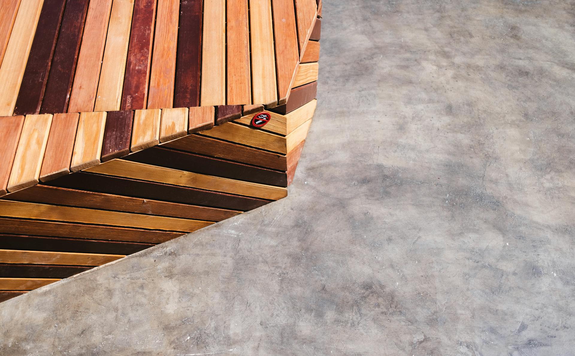 Close-up of a geometric wooden deck meeting a concrete surface, showcasing natural textures and modern design.