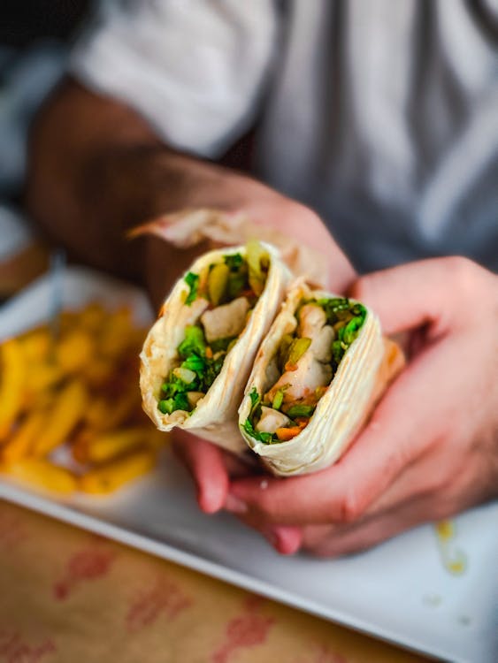 Person Holding a Wrapped Meal with Vegetables Inside Stock Photo