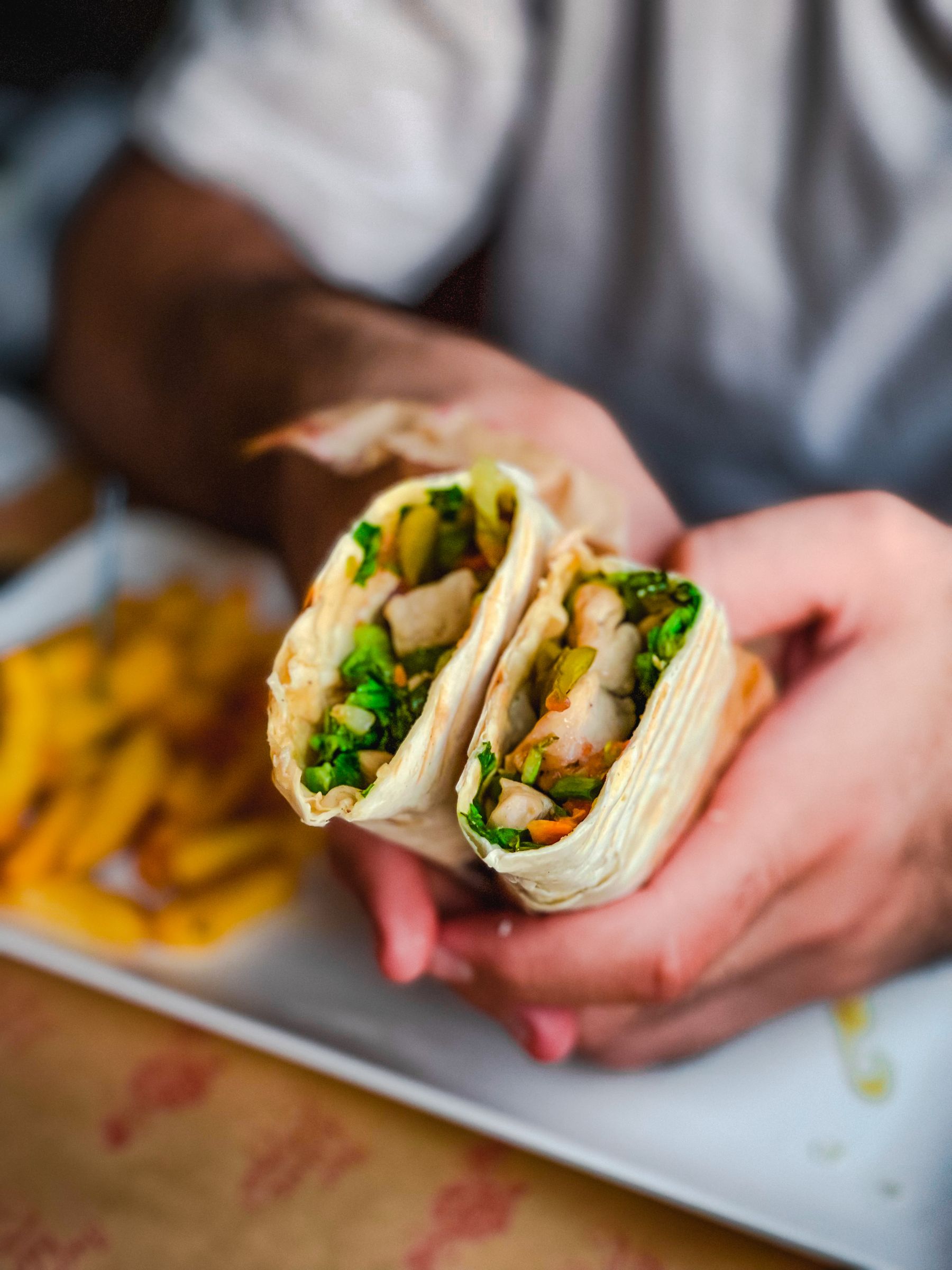 Fresh chicken wrap filled with crisp vegetables, sliced in half