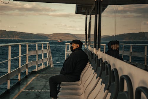 Man Wearing Face Mask Sitting on Ferry
