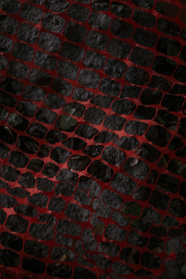 Abstract Image Of A Red Plastic Net And Graphite Ground