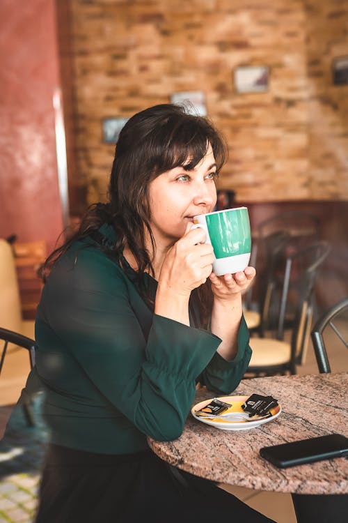 A Woman Drinking a Cup of Coffee while Looking Afar