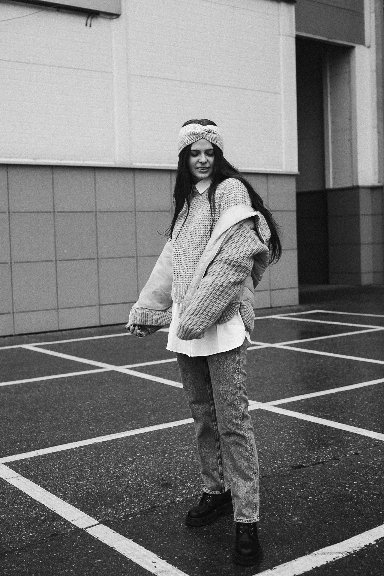 Woman in a layered knit sweater, collared shirt, jeans and boots