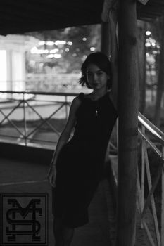 夜晚，一位剪影女子优雅地倚靠在户外的栏杆上