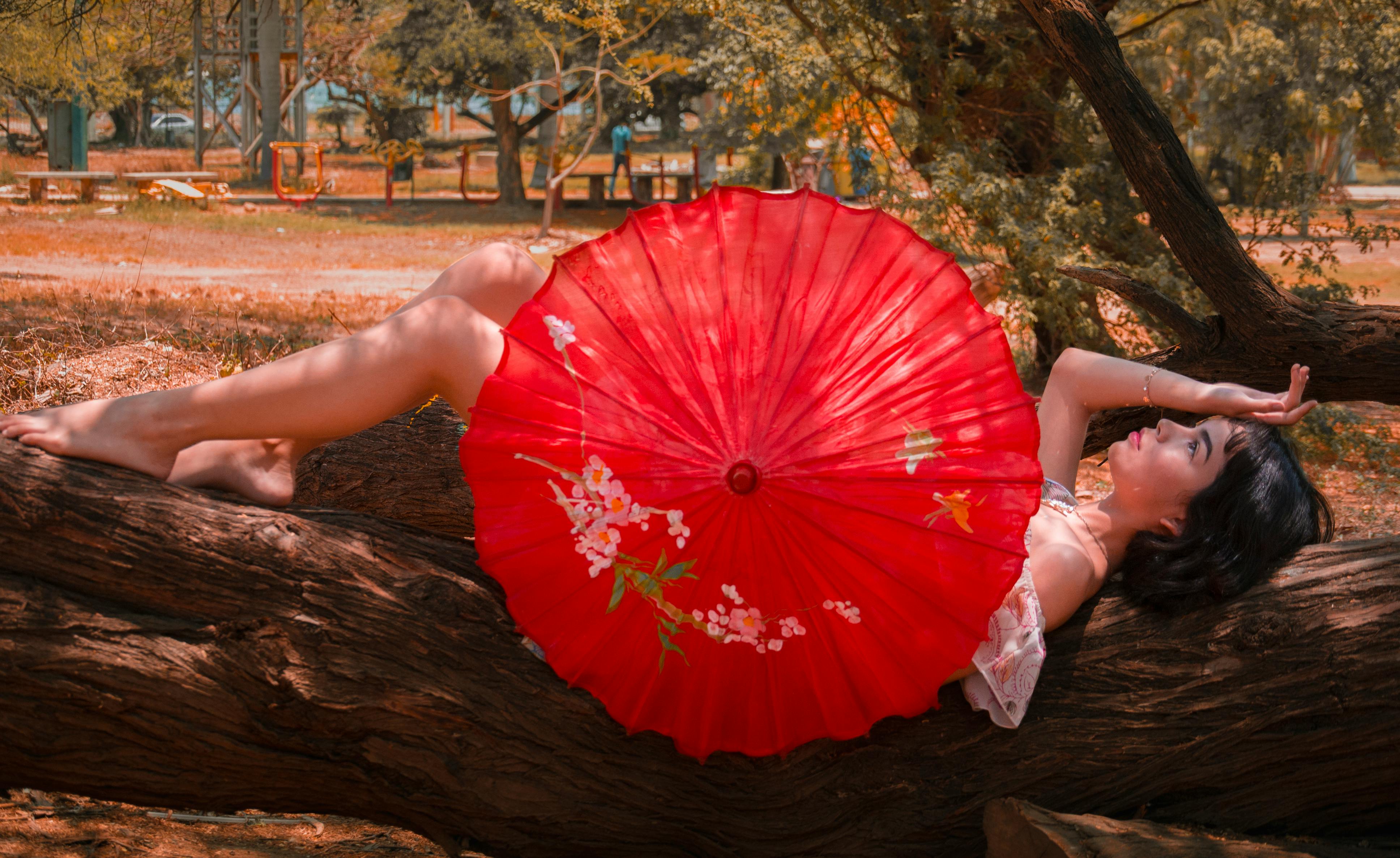 一名女子在委内瑞拉的夏日户外，打着充满活力的红色遮阳伞，悠闲地放松