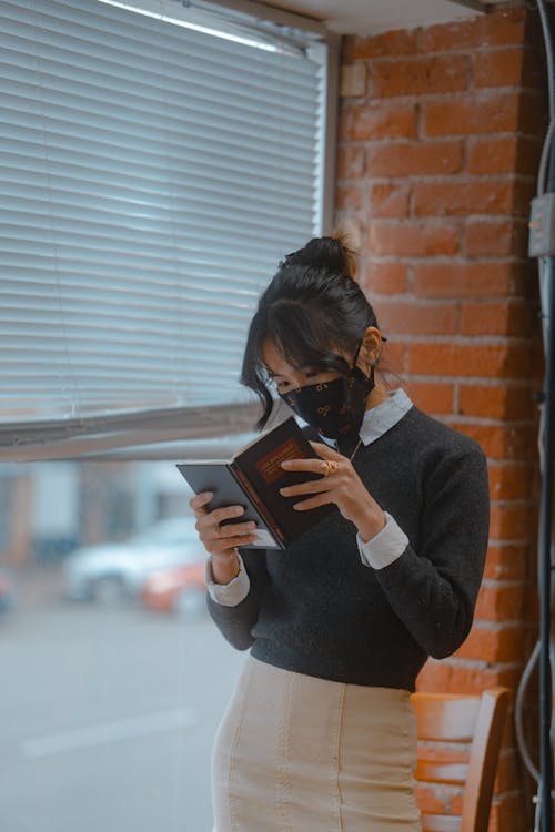 Woman Standing While Reading a Book