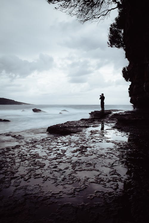 Человек, стоящий на скале возле океана