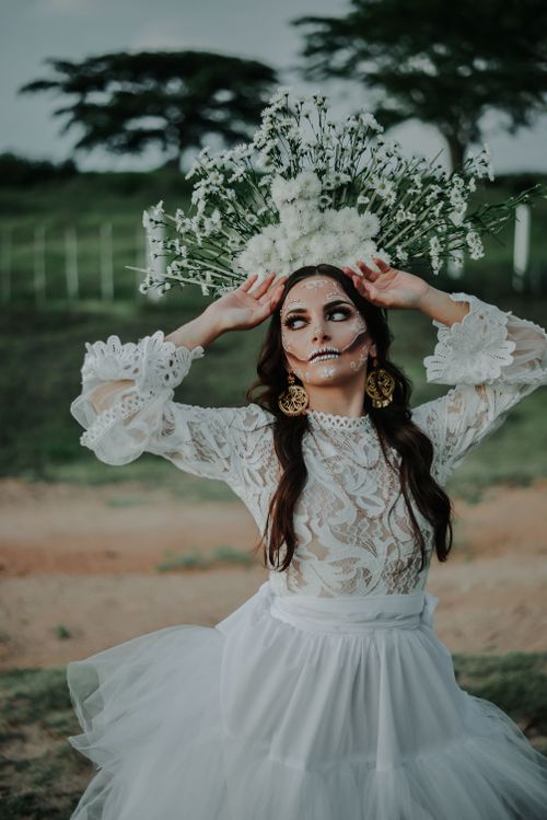 Free Beautiful Catrina in a lace dress with floral headdress, celebrating Día de Muertos outdoors. Stock Photo
