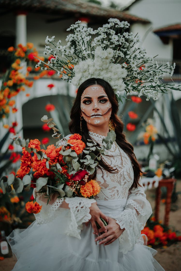 A Bride Wearing Halloween Make Up, Looking At Camera and Holding Flowers 