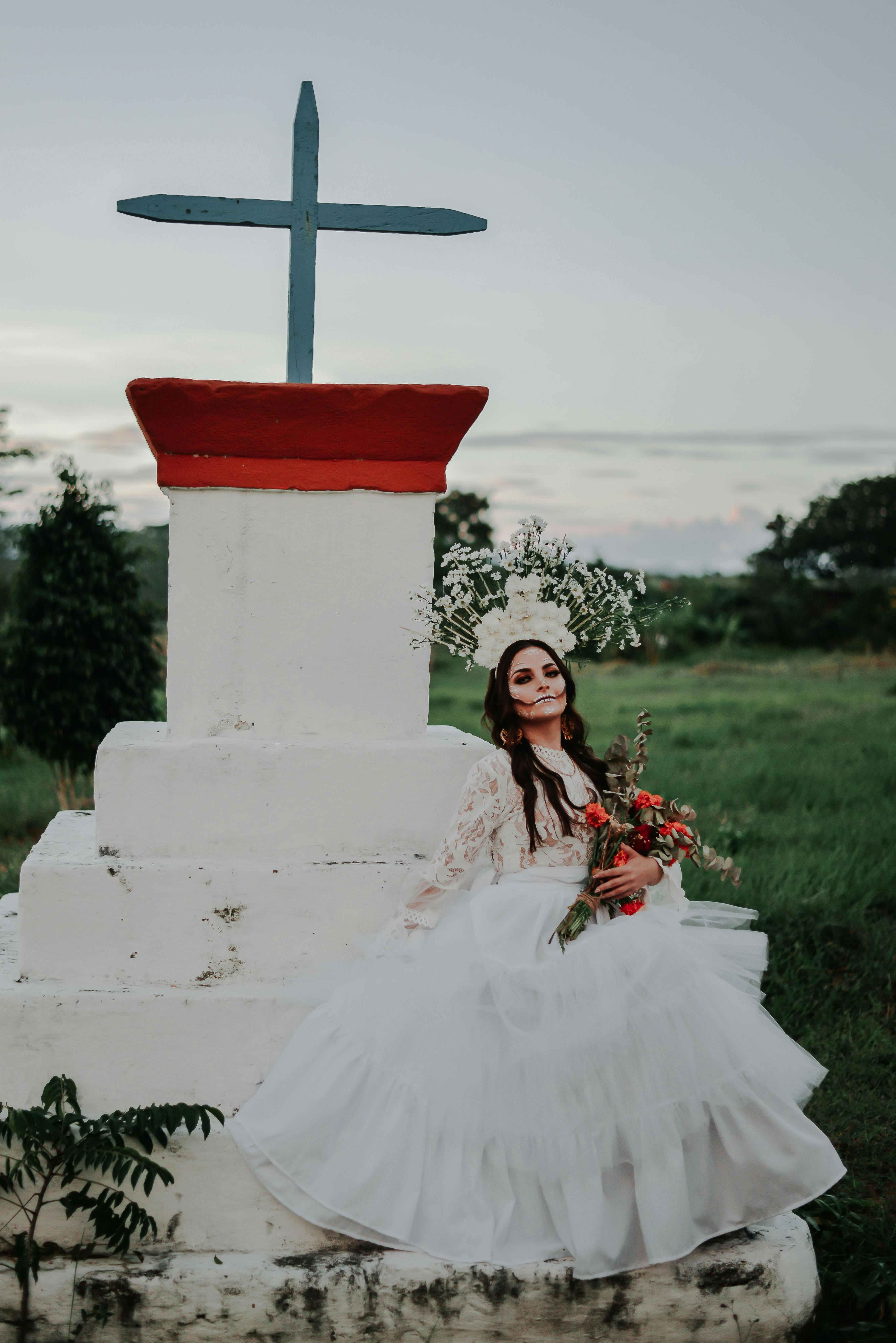 woman in white wedding dress holding red rose bouquet