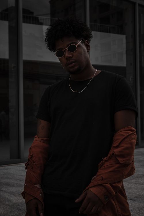Free Urban portrait of a fashionable man wearing sunglasses and a necklace, exuding cool style. Stock Photo