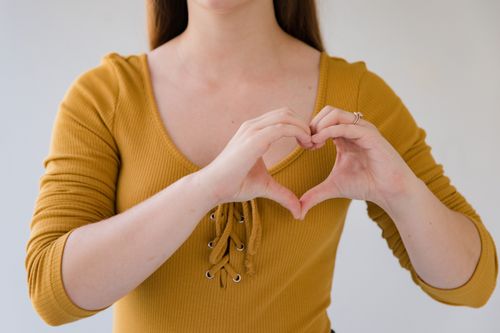 Free Close-up of woman forming a heart with hands, symbolizes love and connection. Stock Photo
