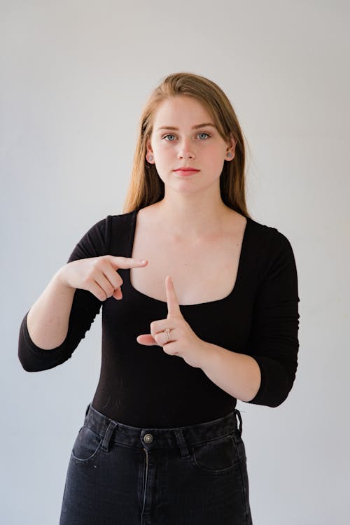 Young Woman in Black Blouse Showing Sign Language Gesture