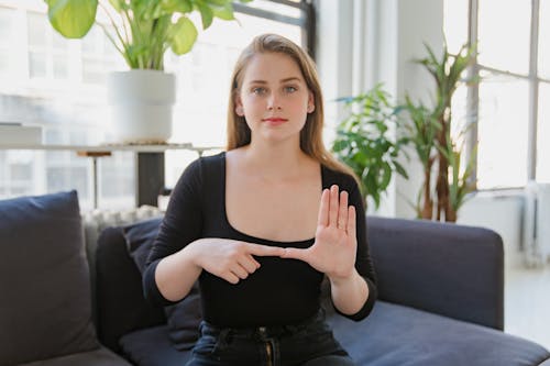Free Portrait of Woman Sitting on Sofa, Showing Sign Language Stock Photo