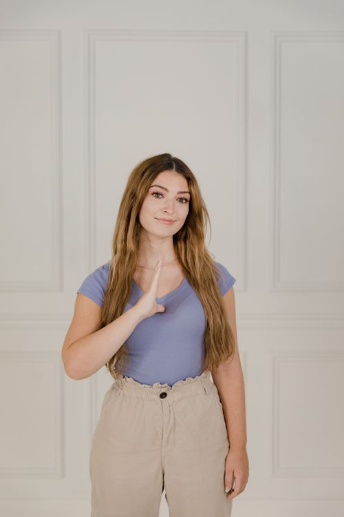 Free Portrait of a smiling woman using sign language indoors, promoting friendly communication. Stock Photo