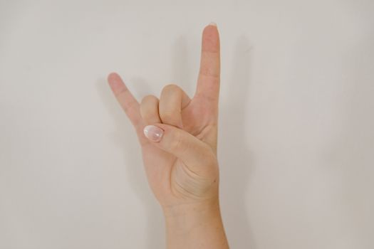 Close-up of hand making 'I Love You' gesture in American Sign Language against white background.
