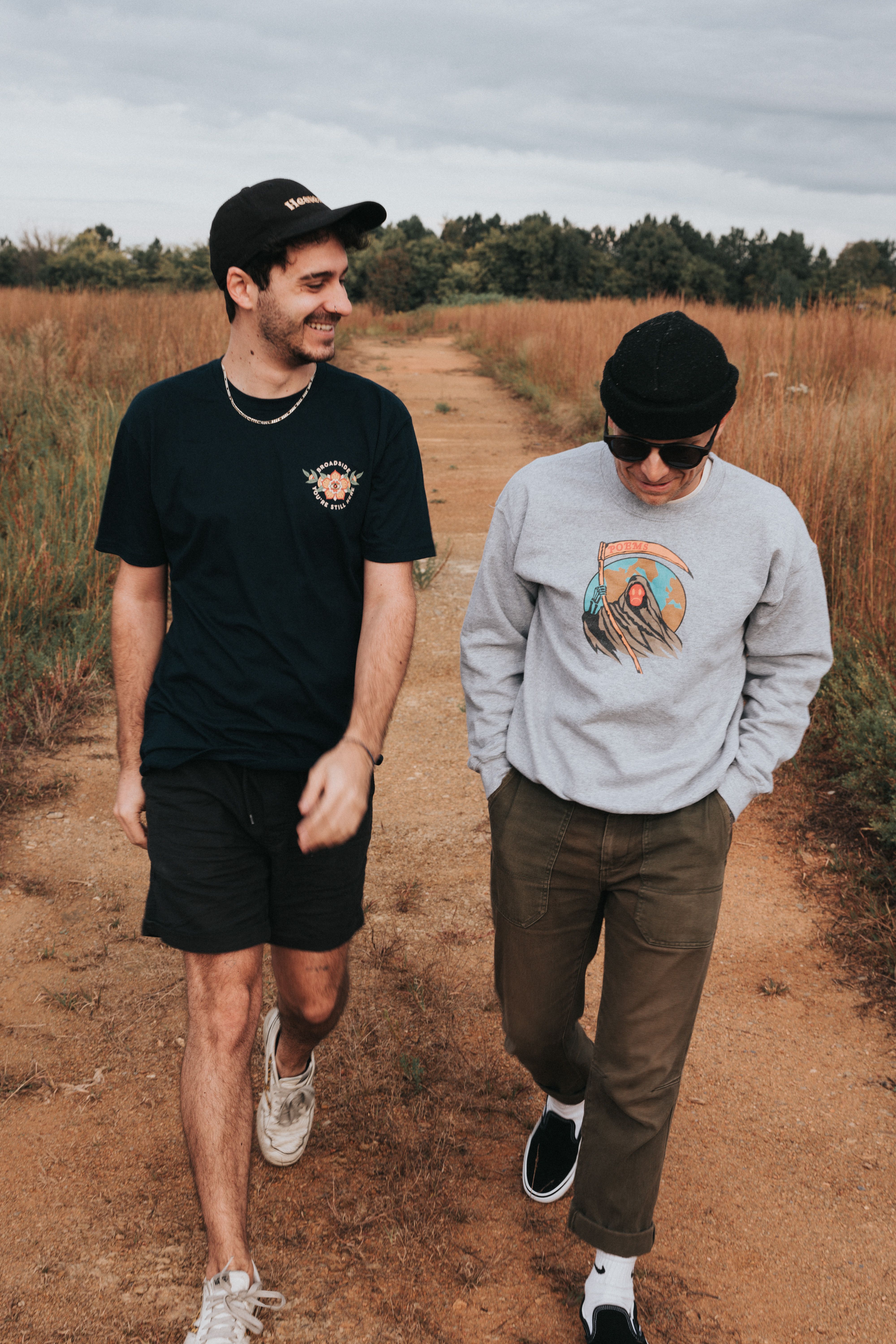 Two young adults happily walking along a nature trail, dressed casually and smiling.