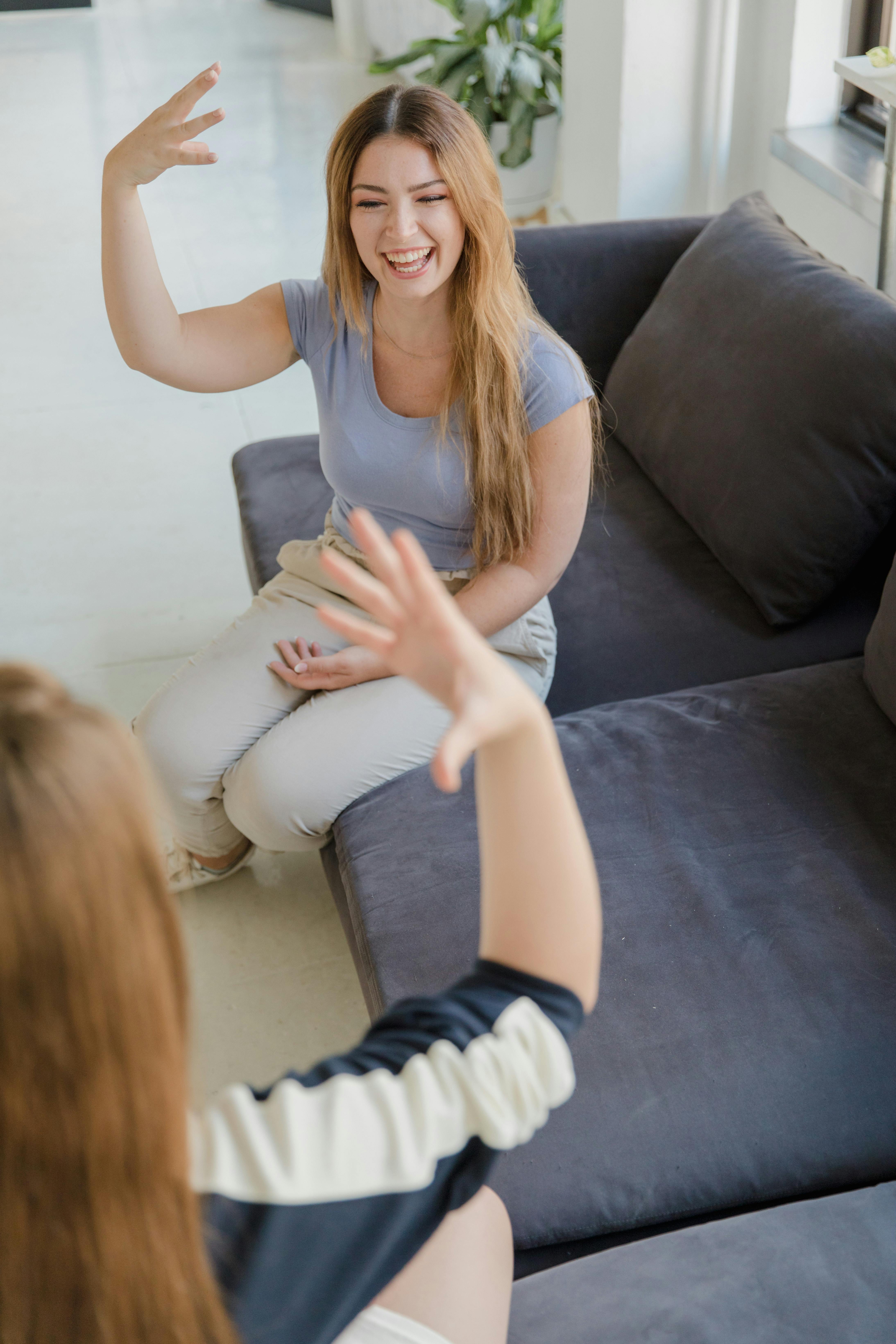 two women sitting on sofa and gesturing