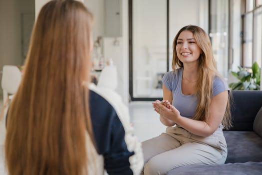 Smiling women having a conversation indoors, gesturing positively.