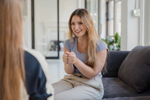 Free Smiling woman engaging in a friendly conversation indoors on a cozy sofa. Stock Photo