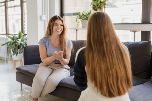 Free Two women having a joyful conversation on a sofa indoors with natural lighting. Stock Photo