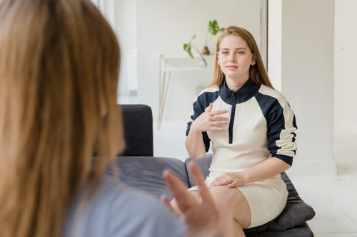 Free Women having a conversation at home, sitting on a sofa in a light living room. Stock Photo